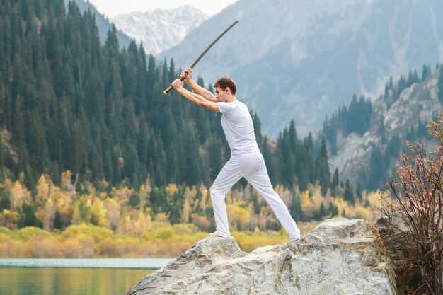 Un homme tient une épée japonaise katana au-dessus de sa tête. Entraînement des compétences de combat.