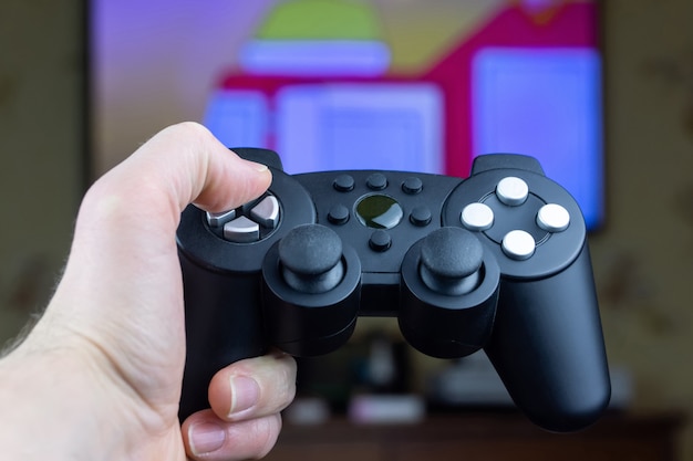 Un homme tient une manette de jeu sans fil à partir d'une console de jeu vidéo dans sa main