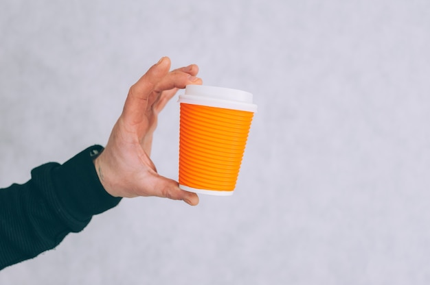 Un Homme Tient Une Maquette D'une Tasse En Papier Pour Le Café Et Le Thé Sur Une Lumière.