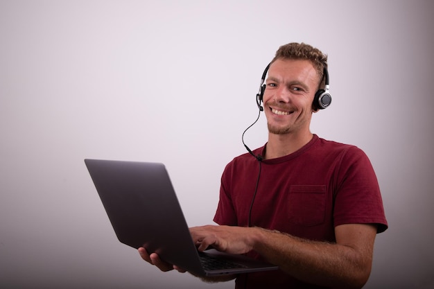 Un homme tient un ordinateur portable et porte des écouteurs avec un microphone call center work studio advertising photo with copy space