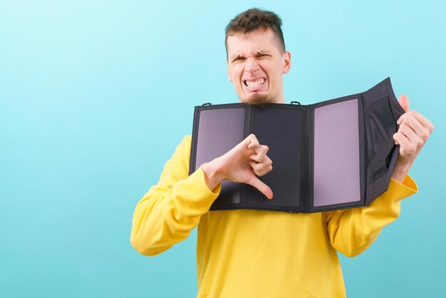 Un homme tient un panneau solaire portable et montre son pouce vers le bas sur un chargeur mobile bleu Green Solar