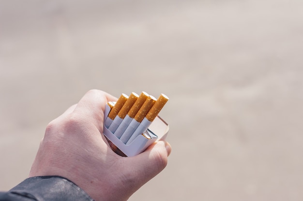 Photo un homme tient un paquet de cigarettes dans ses mains.