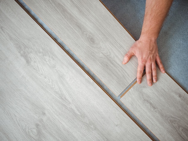 Un homme tient une planche stratifiée dans ses mains. Le processus de réparation dans la chambre