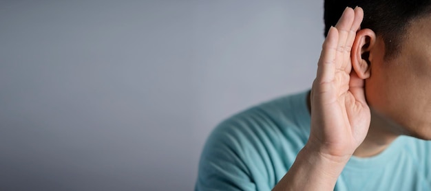 L'homme tient sa main près de l'oreille et écoute attentivement