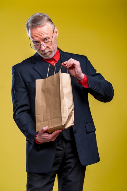 L'homme tient un sac en papier recevant un cadeau. Achats écologiques. Homme en costume.