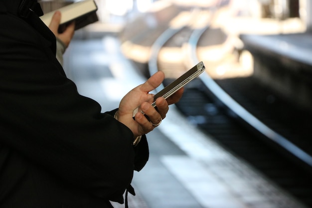 L&#39;homme tient un smartphone, chemin de fer flou de fond.