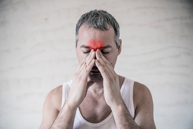 Photo l'homme tient son nez et son sinus avec les doigts dans une douleur évidente d'un mal de tête dans la zone avant du front. douleur des sinus