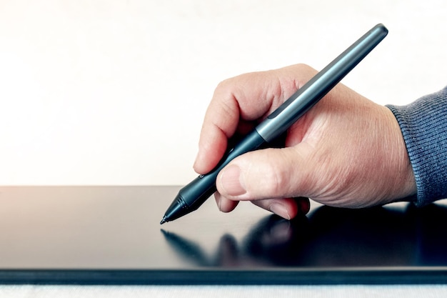 Un homme tient un stylet et dessine avec une tablette graphique