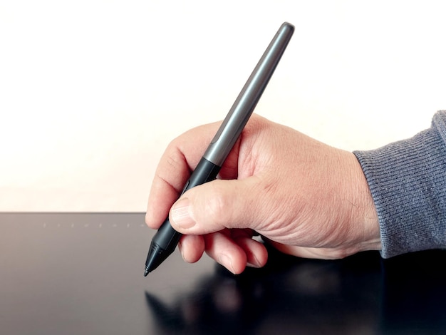 Un homme tient un stylo un stylet et dessine avec une tablette graphique