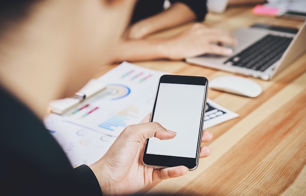 L&#39;homme tient le téléphone sur un bureau en bois