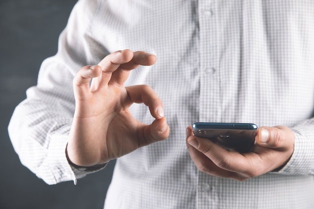 Un homme tient un téléphone et montre un bon signe.