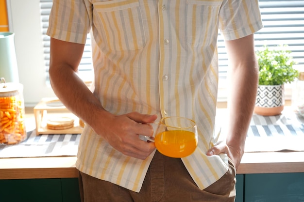 Un homme tient un verre de jus d'orange.