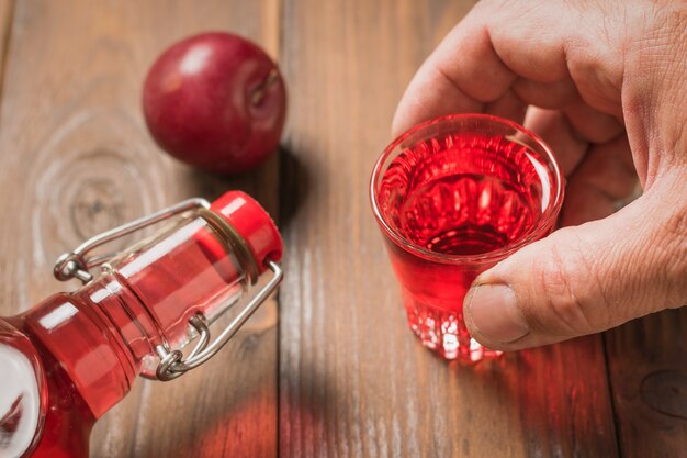 Un homme tient un verre de liqueur de prune sur la table