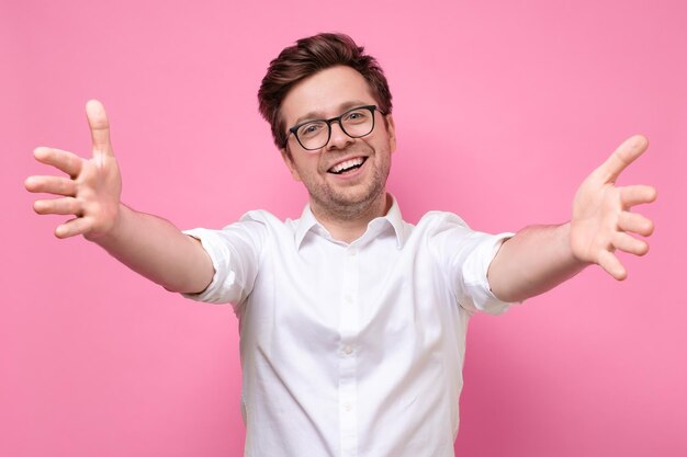 Homme tirant les mains vers vous souriant amicalement à la caméra voulant un câlin