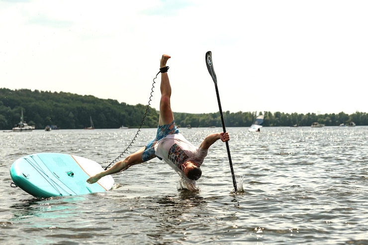 Photo un homme tombe de sa barque à pagaie dans l'eau.