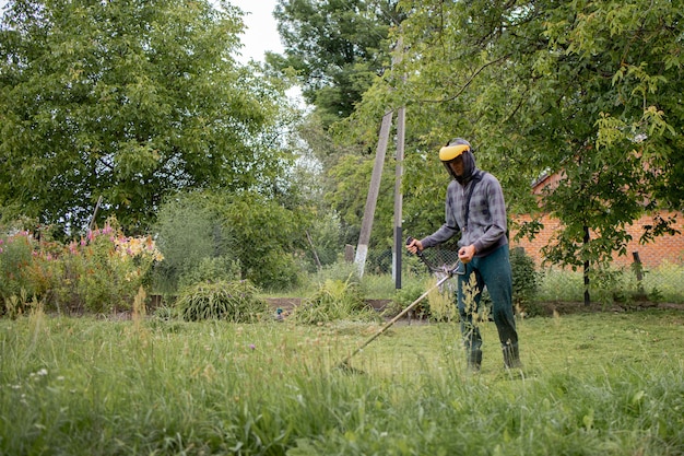 Homme tondre la pelouse dans son jardin