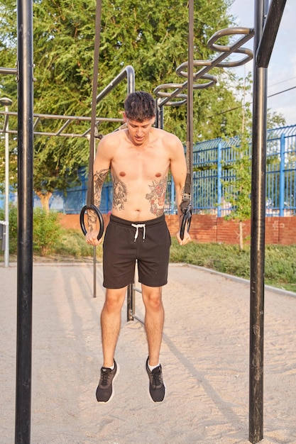 Photo homme torse nu avec des anneaux de formation de tatouages dans le parc