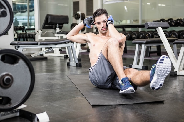 Homme torse nu faisant assis dans la salle de gym