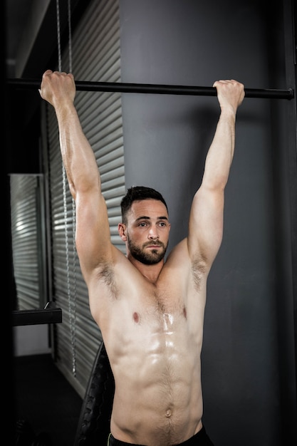 Homme torse nu faisant pull up au gymnase de crossfit