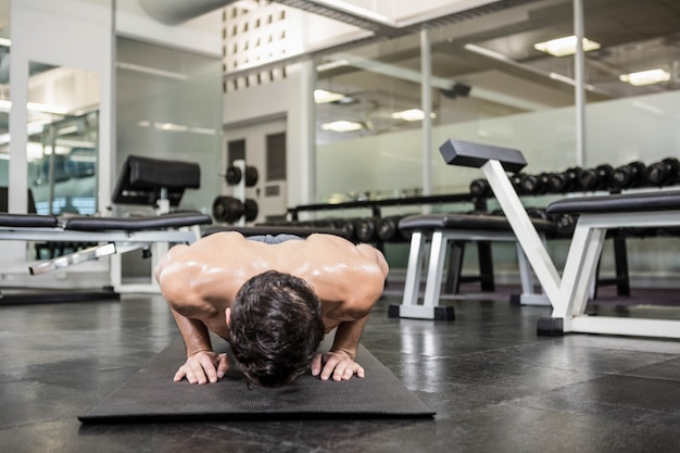 Homme torse nu faisant push up à la gym