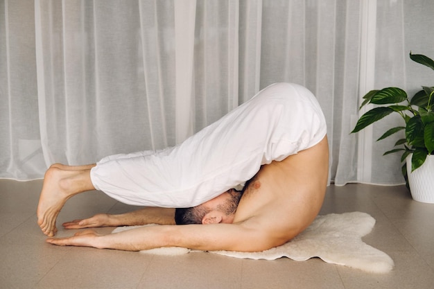 Un homme avec un torse nu fait du yoga dans une salle de fitness le concept d'un mode de vie sain