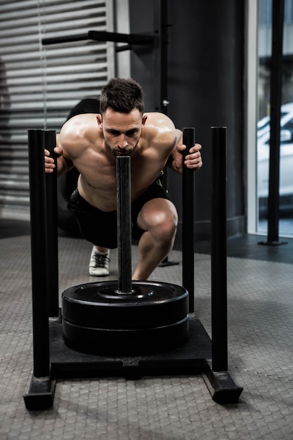 Homme torse nu poussant des poids lourds au gymnase de crossfit