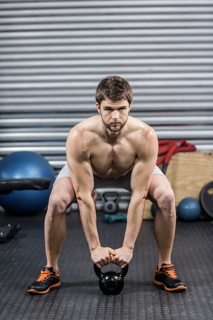 Homme torse nu, soulevant des haltères au gymnase de crossfit