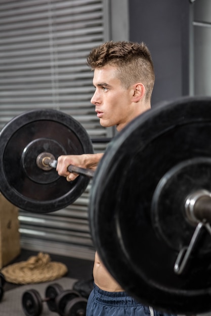 Homme torse nu, soulevant des haltères au gymnase de crossfit