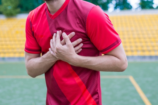 Homme touchant le côté gauche du corps sur fond de stade