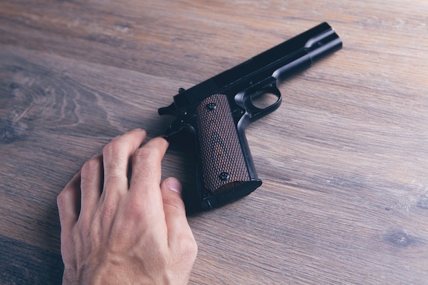 Homme touchant le pistolet sur la table en bois