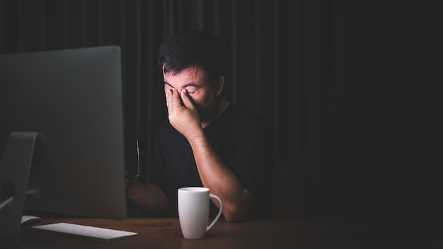 Homme touchant ses yeux à cause de son travail sur ordinateur