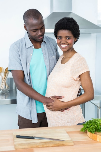 Homme touchant le ventre d'une femme enceinte dans la cuisine à la maison