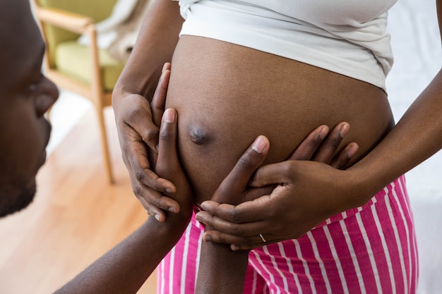 Homme touchant le ventre de femme enceinte à la maison