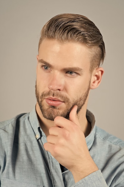 L'homme touche la barbe sur le visage non rasé