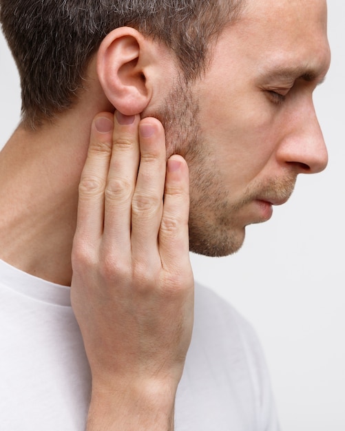 L'homme touche les glandes lymphatiques avec ses doigts près de l'oreille