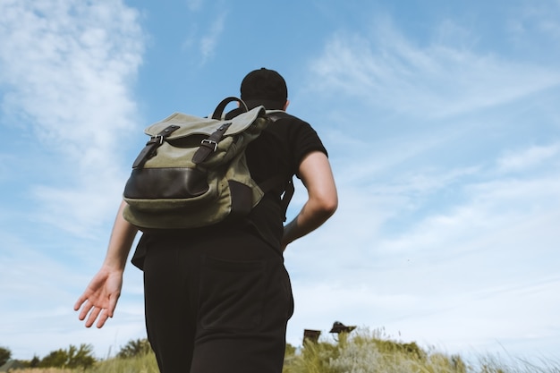 Un homme touriste avec un sac à dos escalade une montagne