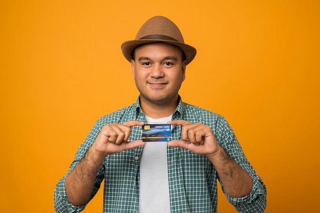 Homme de touriste en vacances tenant une carte de crédit isolée sur jaune
