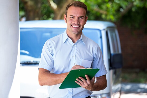 Homme à tout faire debout près de sa camionnette de livraison