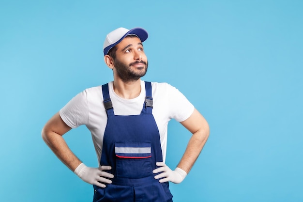 Homme à tout faire réfléchi en salopette levant les yeux rêvant avec une expression inspirée heureuse faisant un vœu Profession de l'industrie des services livraison de courrier entretien ménager entretien studio tourné isolé