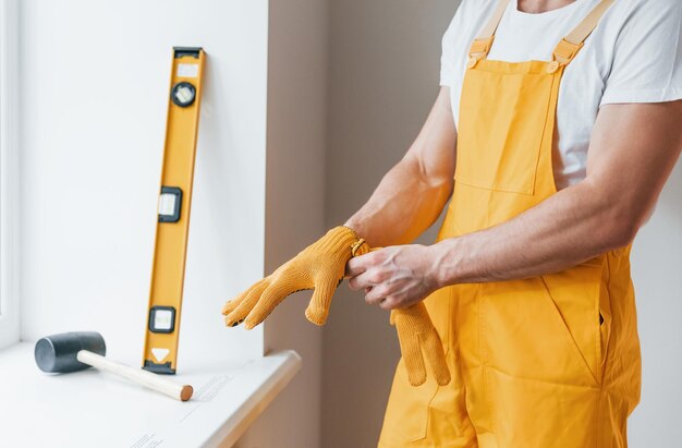 Homme à tout faire en uniforme jaune se préparant à travailler à l'intérieur Conception de rénovation de maison