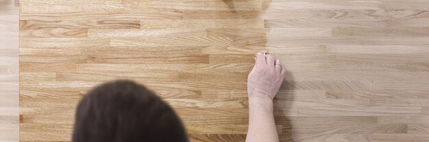 L'homme traite la surface en bois de la table avec un vernis protecteur