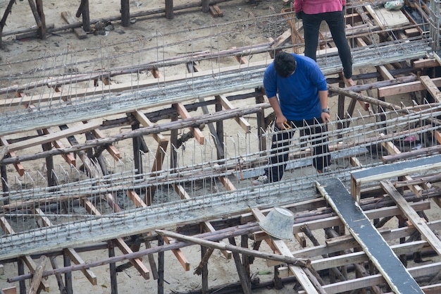 Un homme travaillant avec des armatures en acier d&#39;armature dans la structure en béton de poutre de bâtiment à la maison