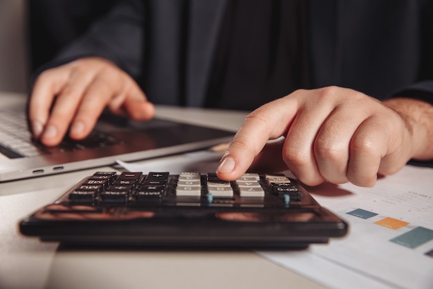 Homme travaillant au bureau à l'aide de la calculatrice. Concept d'entreprise. Fermer