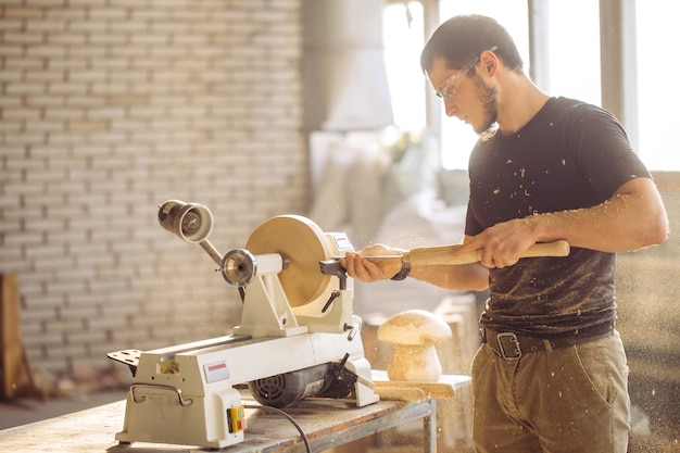 Homme travaillant au petit tour à bois, un artisan sculpte un morceau de bois