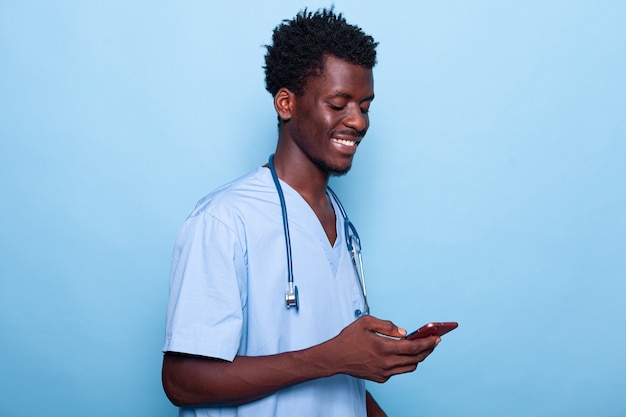 Homme travaillant comme infirmière regardant un smartphone et souriant