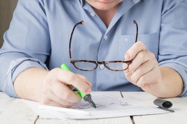 Homme travaillant à domicile, avec des documents et un stylo surligneur