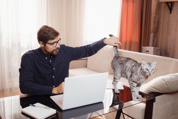 Homme travaillant à domicile sur ordinateur portable Bureau à domicile avec chat