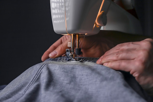 Homme travaillant avec du denim sur une machine à coudre close up fashion design