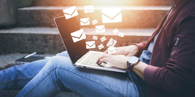 Homme travaillant à l'extérieur à l'aide d'un ordinateur portable avec des icônes de communication icône de lettre icônes d'e-mail et e-mail de newsletter et protégez vos informations personnelles ou spams contact du centre d'appels du service client