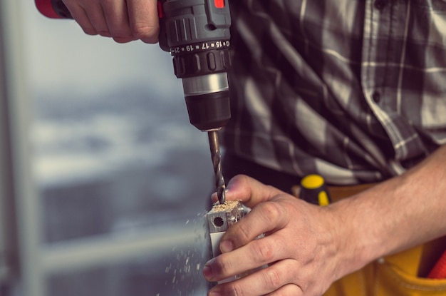 Homme travaillant à faire des trous dans la planche avec une perceuse pendant le processus de fabrication de meubles